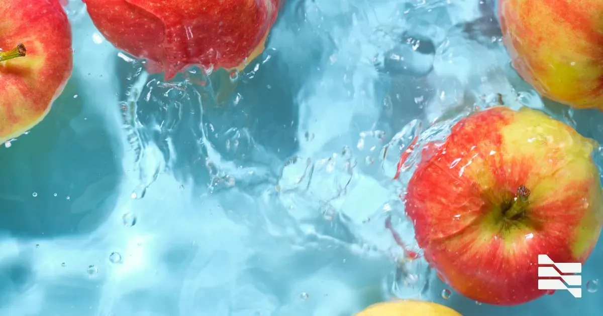 Bright red apples splashing into clear blue water, symbolizing fresh ideas in freelance designer portfolios.