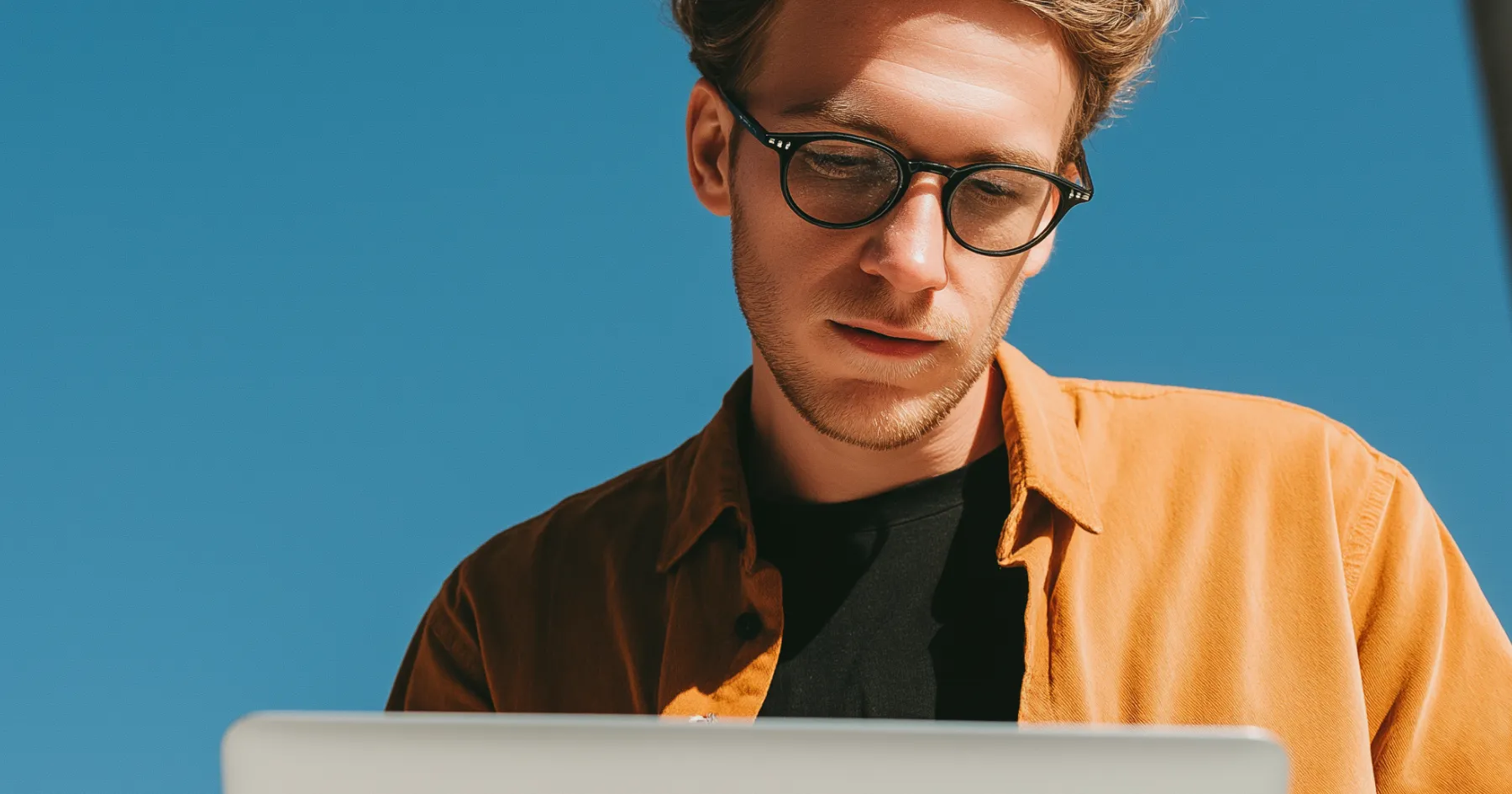 A man in glasses focused on a laptop