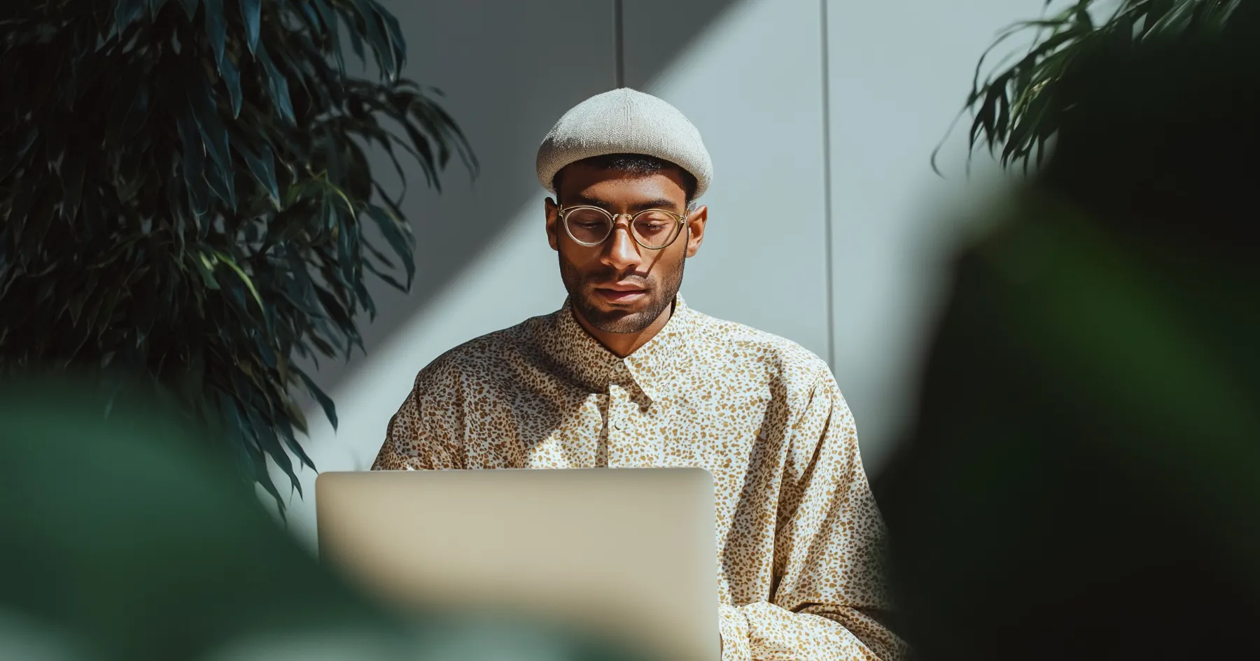A man in a flat cap working on a laptop