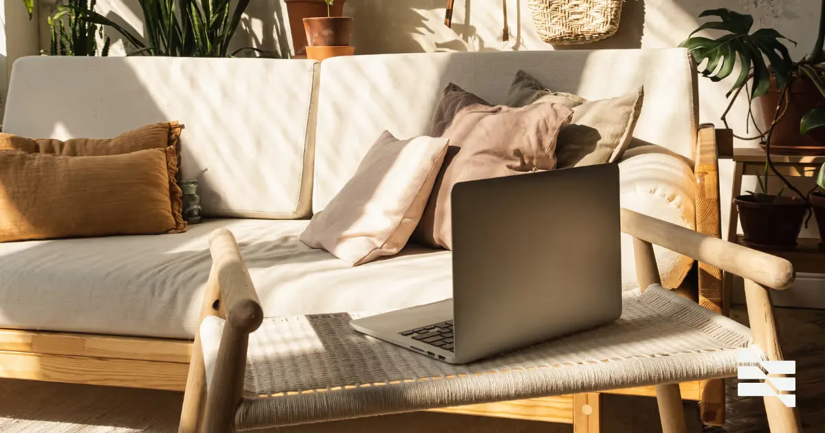An open laptop on a sofa in a sunlit living room