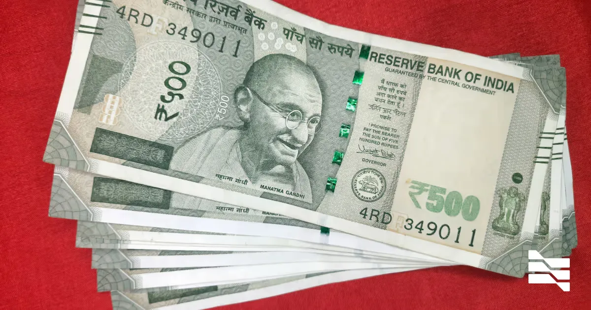 A stack of Indian 500 rupee banknotes on a red surface
