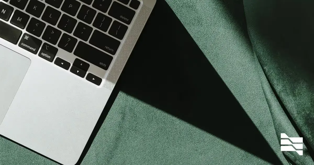 Close-up of a laptop on a green fabric surface with contrasting shadows, symbolizing innovative 'Company as a Service' models.