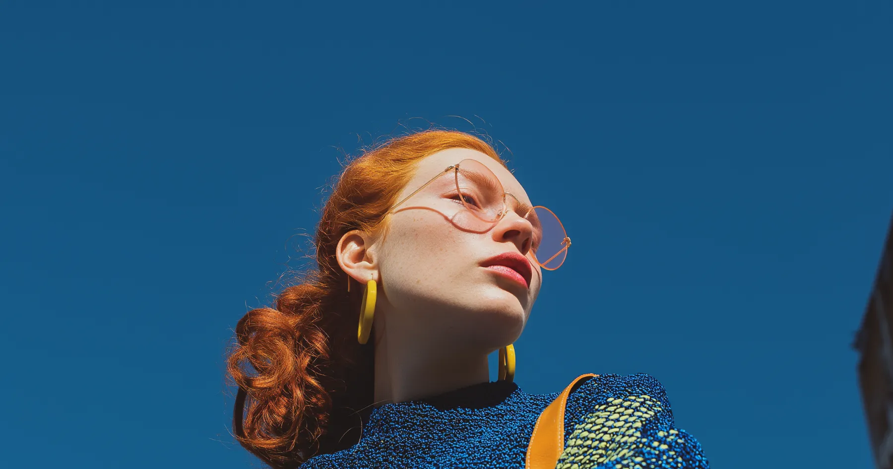 A red-haired person in blue knitwear against a blue background